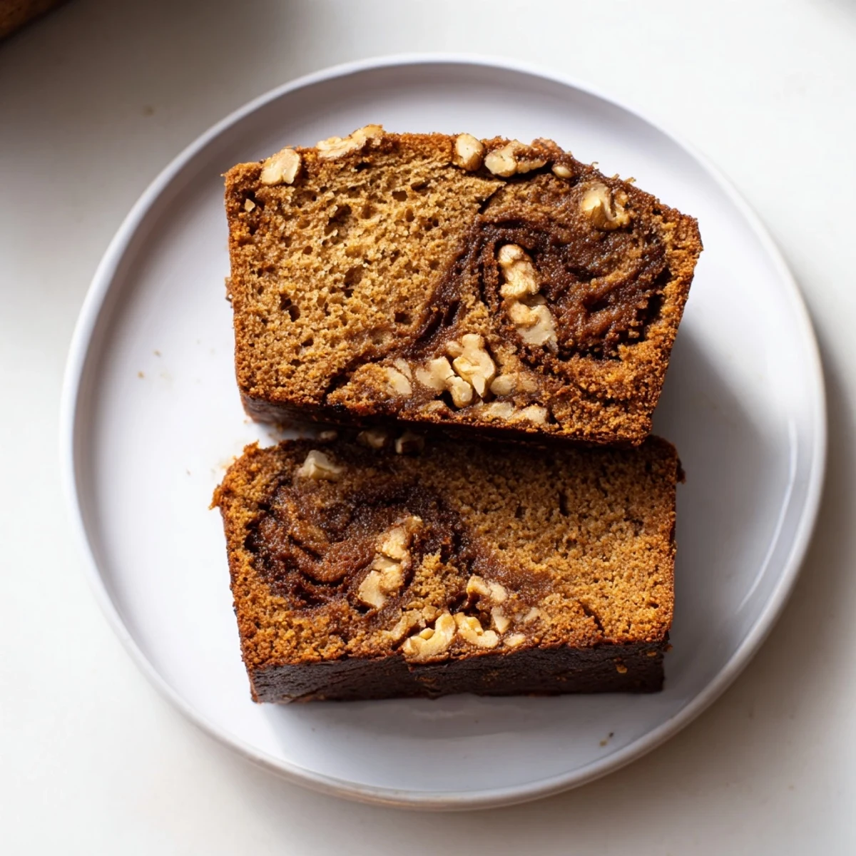 A close-up of moist pumpkin bread, perfect for a fall snack, served with whipped cream.