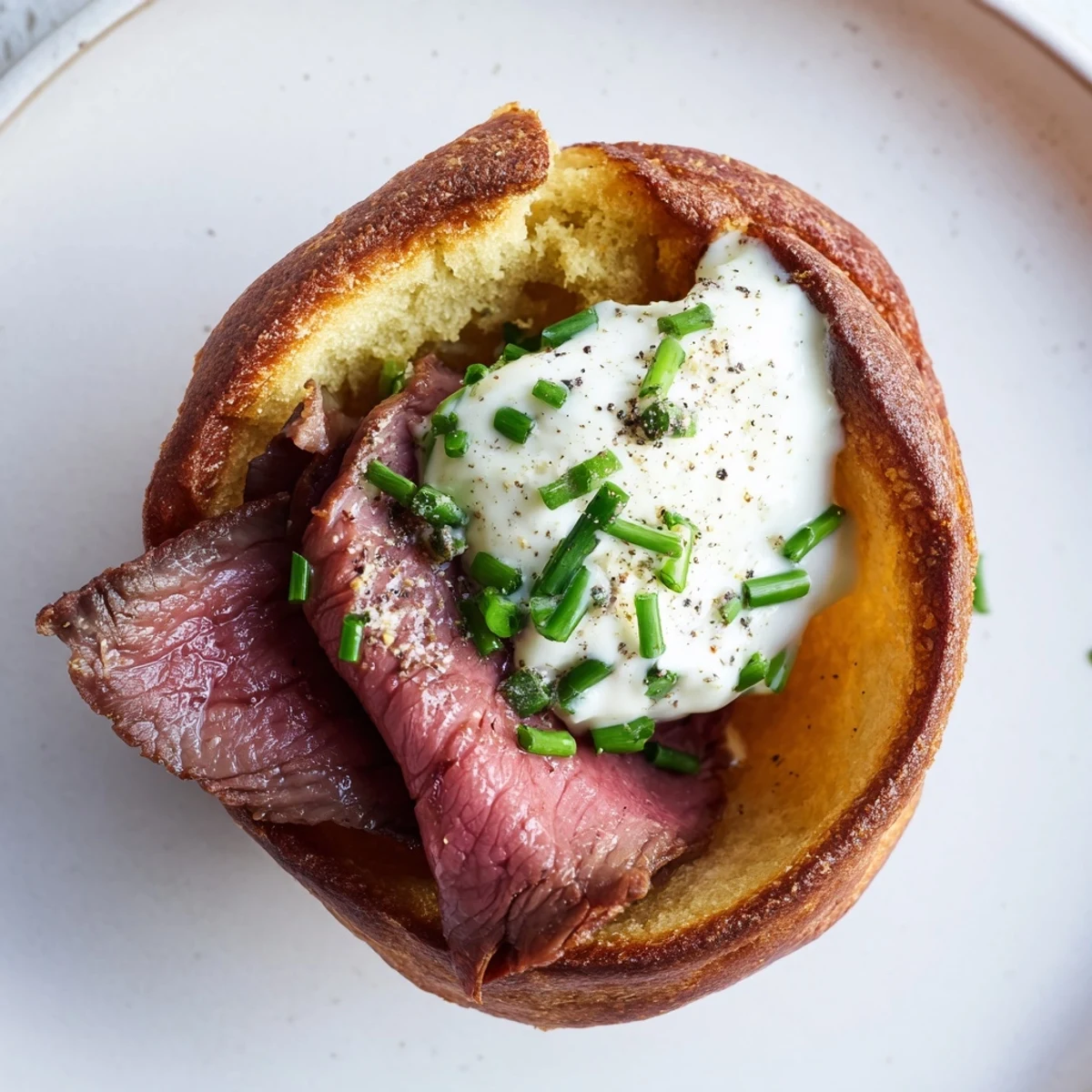 Express Holiday Yorkshire Pudding Bites, golden and puffy, filled with savory roast beef and garnished with fresh chives.