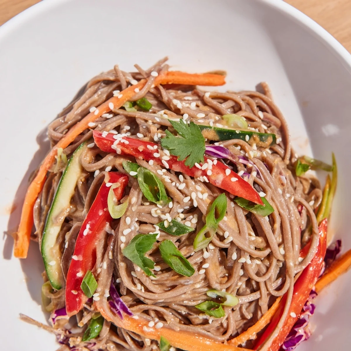 Enjoy a healthy bowl of chilled soba noodle salad with crunchy vegetables, drizzled in savory sauce.