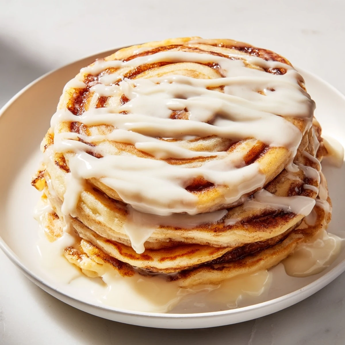 Warm and golden Cinnamon Roll Pancakes with a swirl of cinnamon, ready to be enjoyed.