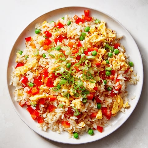 Golden, fluffy Egg Fried Rice: a tempting stir-fry featuring egg-coated rice, fresh veggies, and savory sauce.