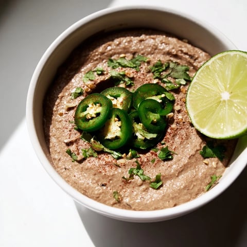 Creamy Spicy Black Bean Dip, garnished with cilantro, is perfect for dipping tortilla chips at a party.