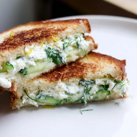 A close-up view of a grilled cheese sandwich on a rustic board, showcasing the melty, savory filling inside.