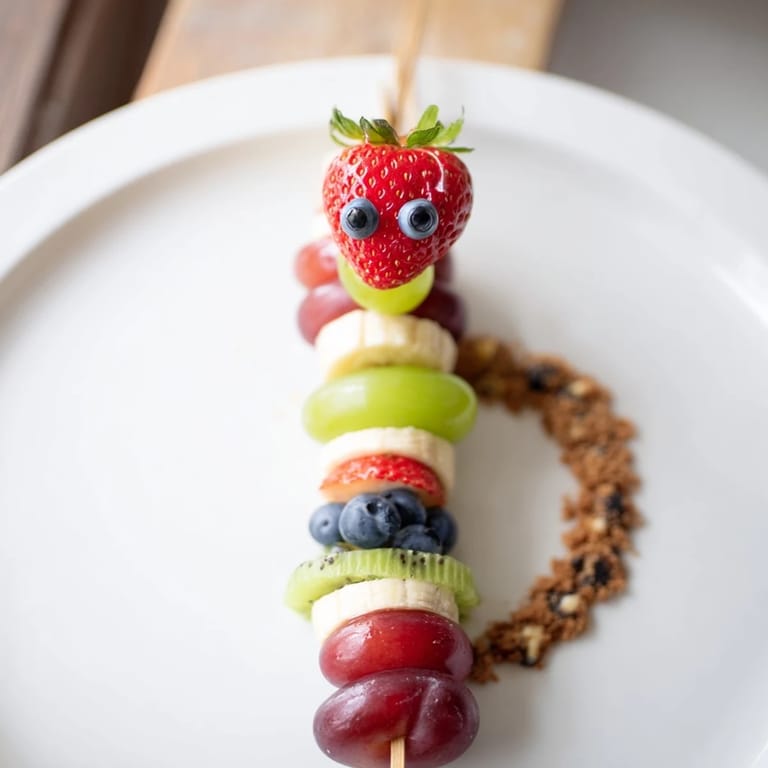 Freshly made Caterpillar Fruit Skewer Track, featuring bright fruit skewers arranged on a chocolatey cookie track.
