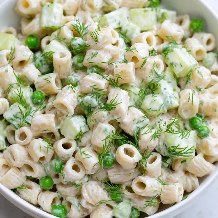 Close-up view of Creamy Dill Pickle Pasta Salad showing creamy dressing coating the pasta, pickles, peas, and crunchy celery.