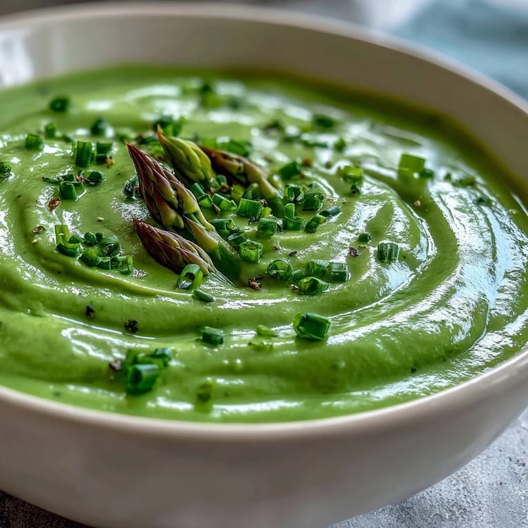 Vibrant green Asparagus Soup with a silky cream finish, served alongside warm crusty bread for dipping.