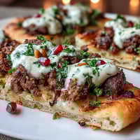 Warm spiced lamb flatbread pizza with creamy yogurt, pomegranate seeds, and fresh mint, baked to golden perfection for a flavorful Middle Eastern meal.